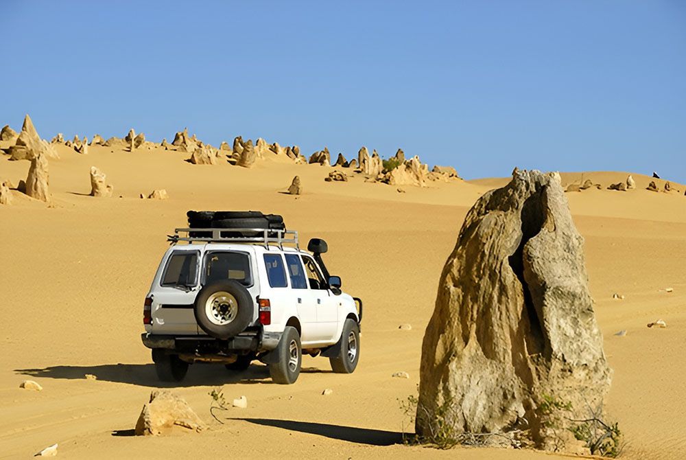 White SUV Vehicle Parked In The Middle Of A Desert Next To A Large Rock — MB Automotive In Garbutt, QLD