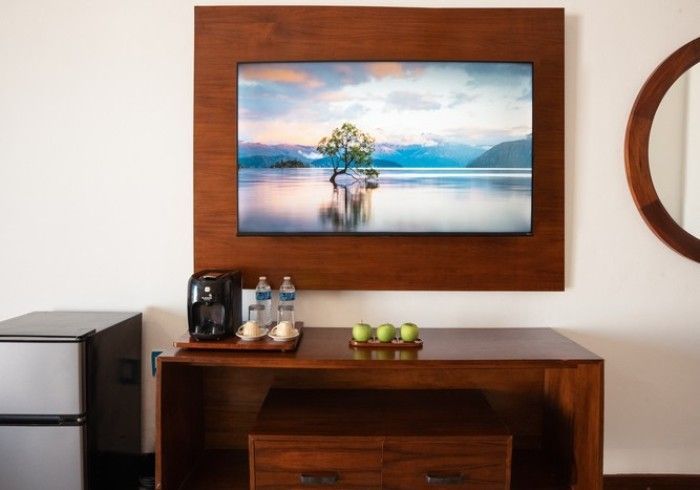 Pared de la habitación del hotel con un paisaje lacustre enmarcado sobre una cómoda de madera y un rincón para el café.