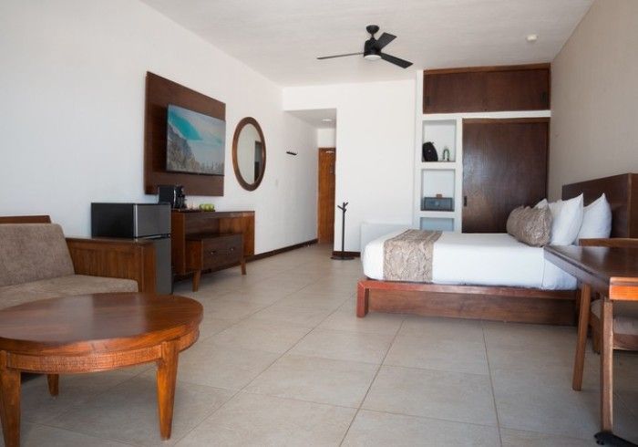 Habitación luminosa y moderna con cama, televisor, muebles de madera y suelo de baldosas.