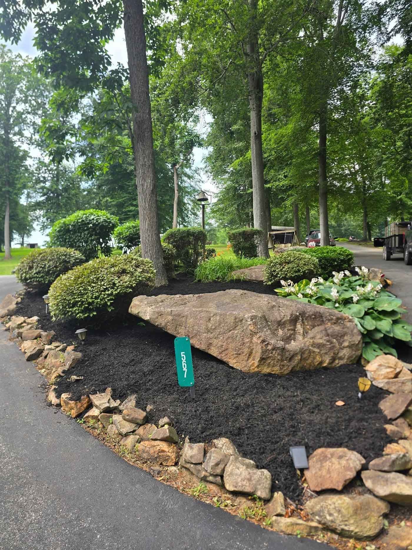 Stone and landscaping with a sign for hole 3 at a golf course, bordered by trees and lush greenery.