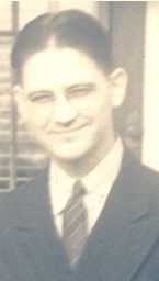 A man in a suit and tie is smiling in a black and white photo.
