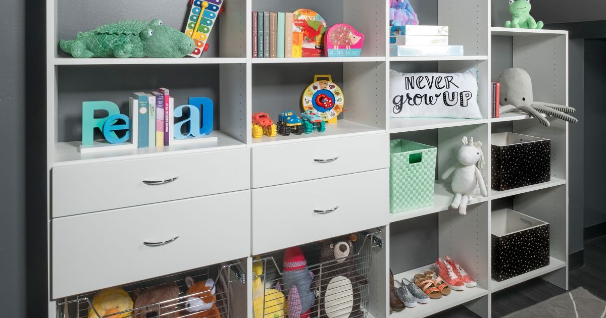 A white storage shelving unit with drawers and open compartments filled with toys, books, and decorative bins.