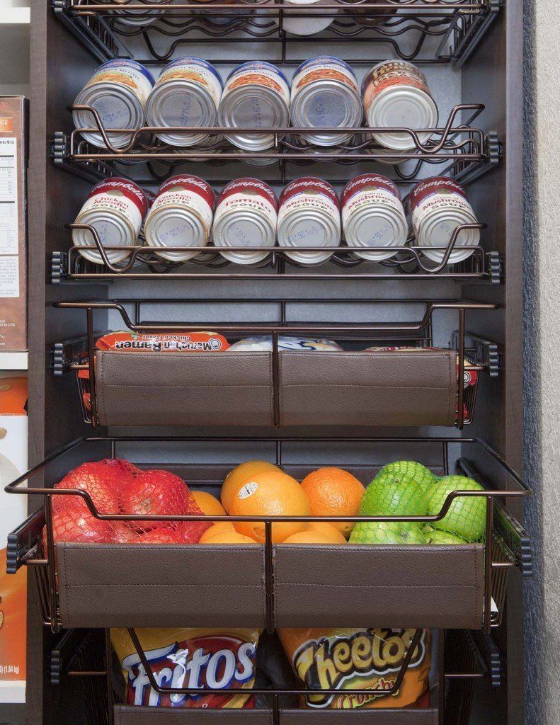 A tall pantry cabinet with sliding wire racks containing canned goods, fresh fruit, and bags of chips.