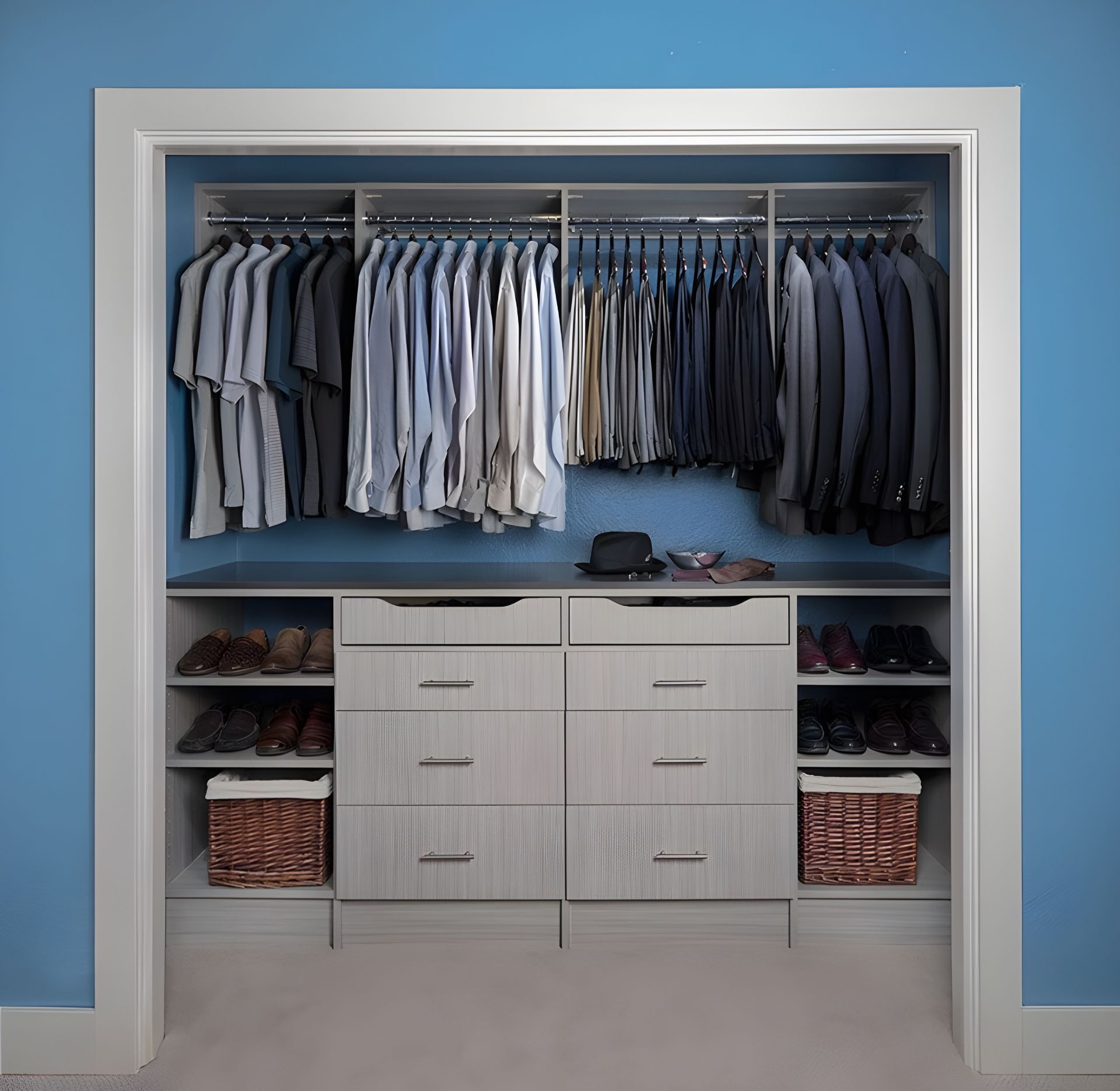 A reach-in closet featuring hanging shirts and suits above a central dresser with drawers, flanked by shelves and baskets.