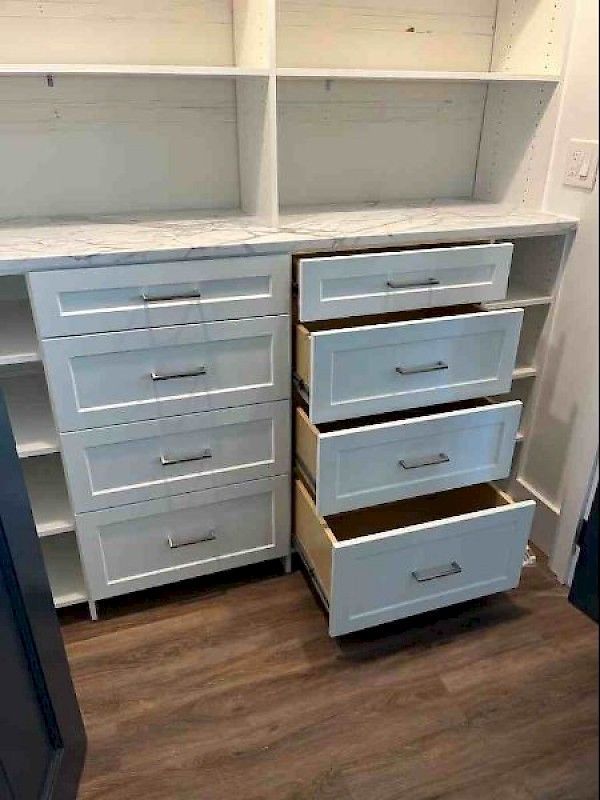 White built-in storage unit with marble-style countertop, closed drawers on the left, and open drawers on the right.