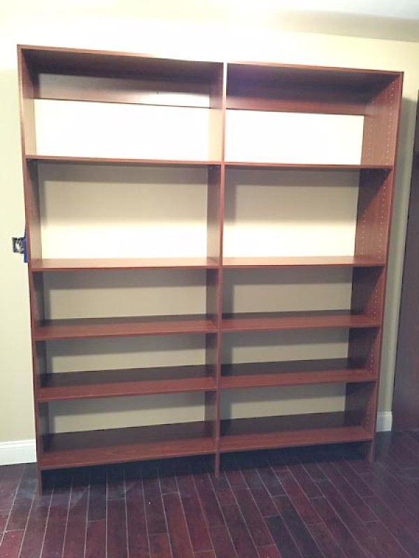 Empty, tall, dark wood double bookshelf with five shelves in each section against a neutral wall on a wood floor.