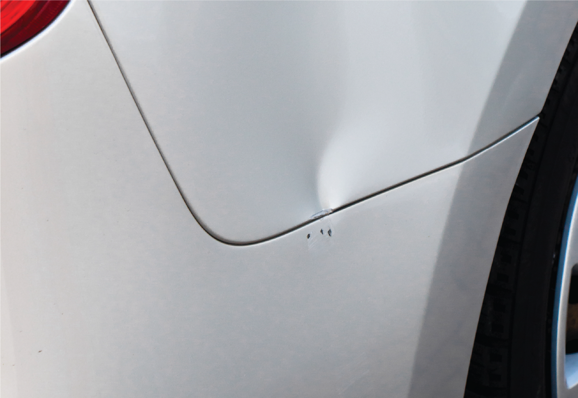 A man is polishing the hood of a blue car.