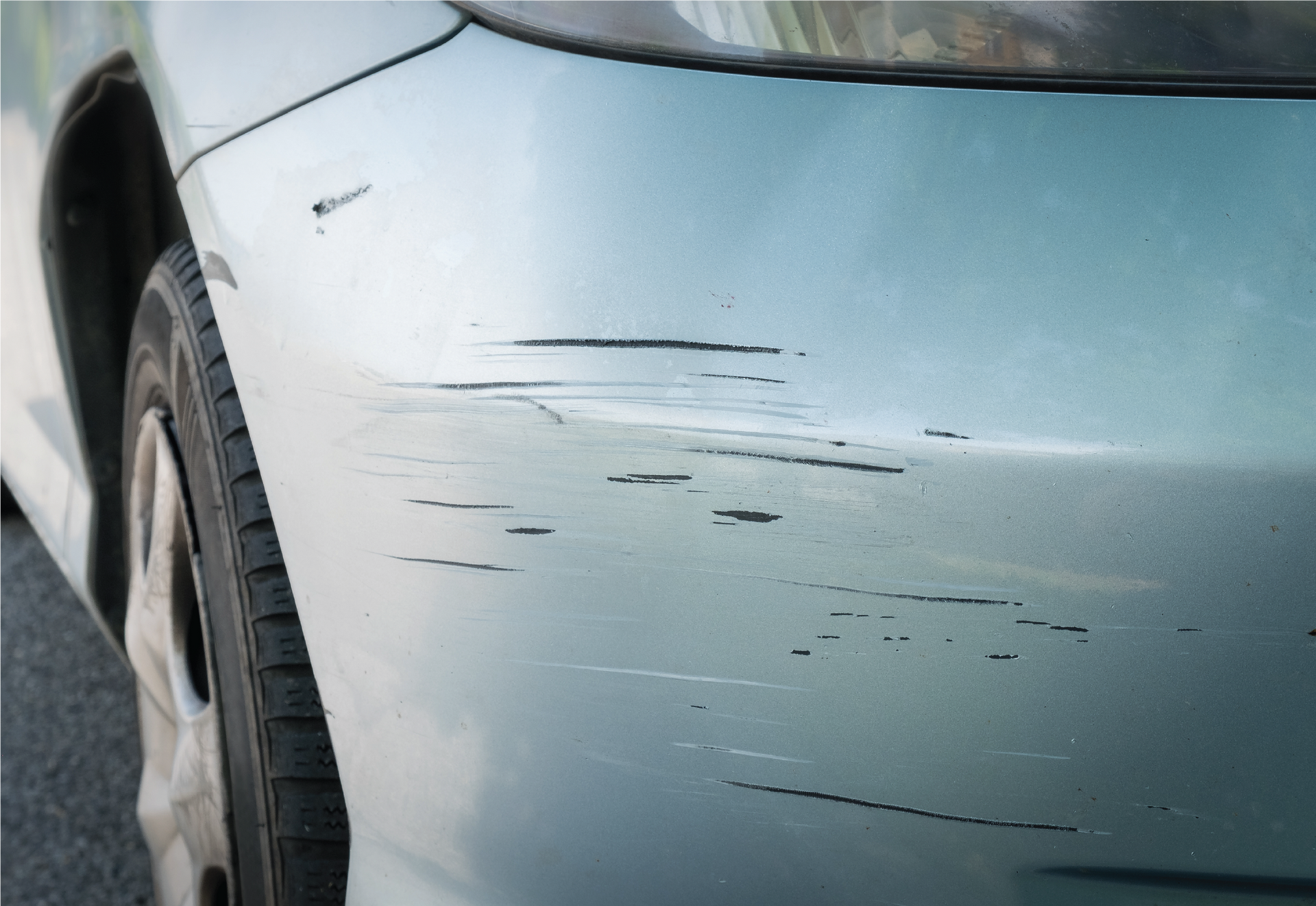 A man is polishing the hood of a blue car.