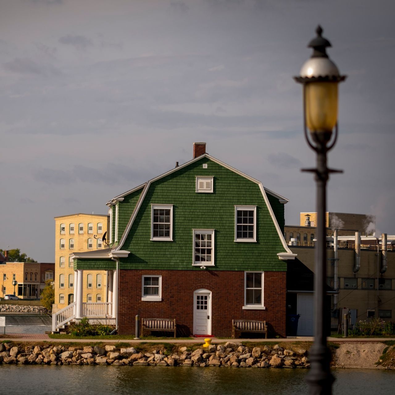 a wooden walkway leading to a gazebo overlooking a body of water at sunset .