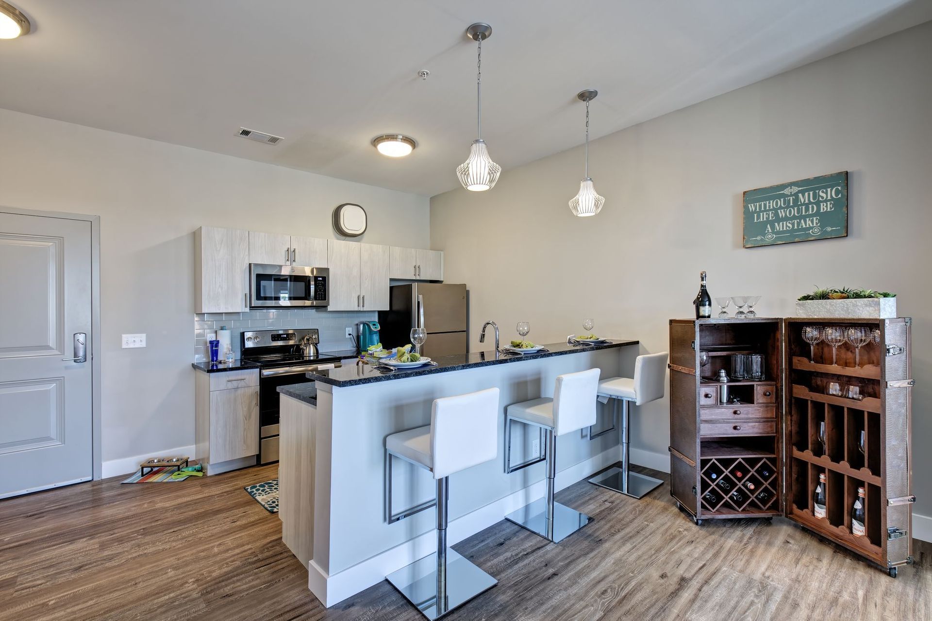 A kitchen with a bar and stools and a wine rack.