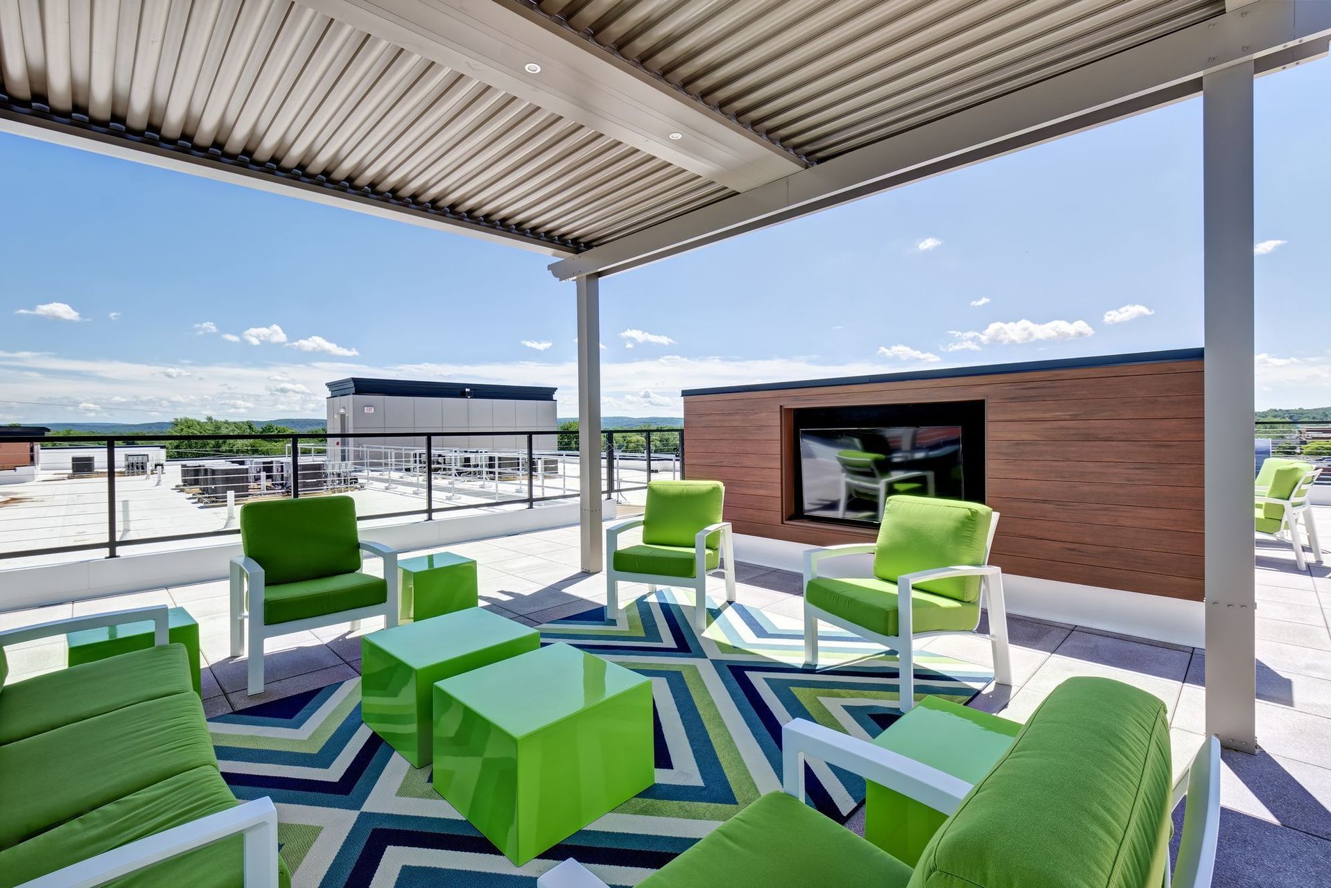 A patio with green chairs and tables under a canopy.