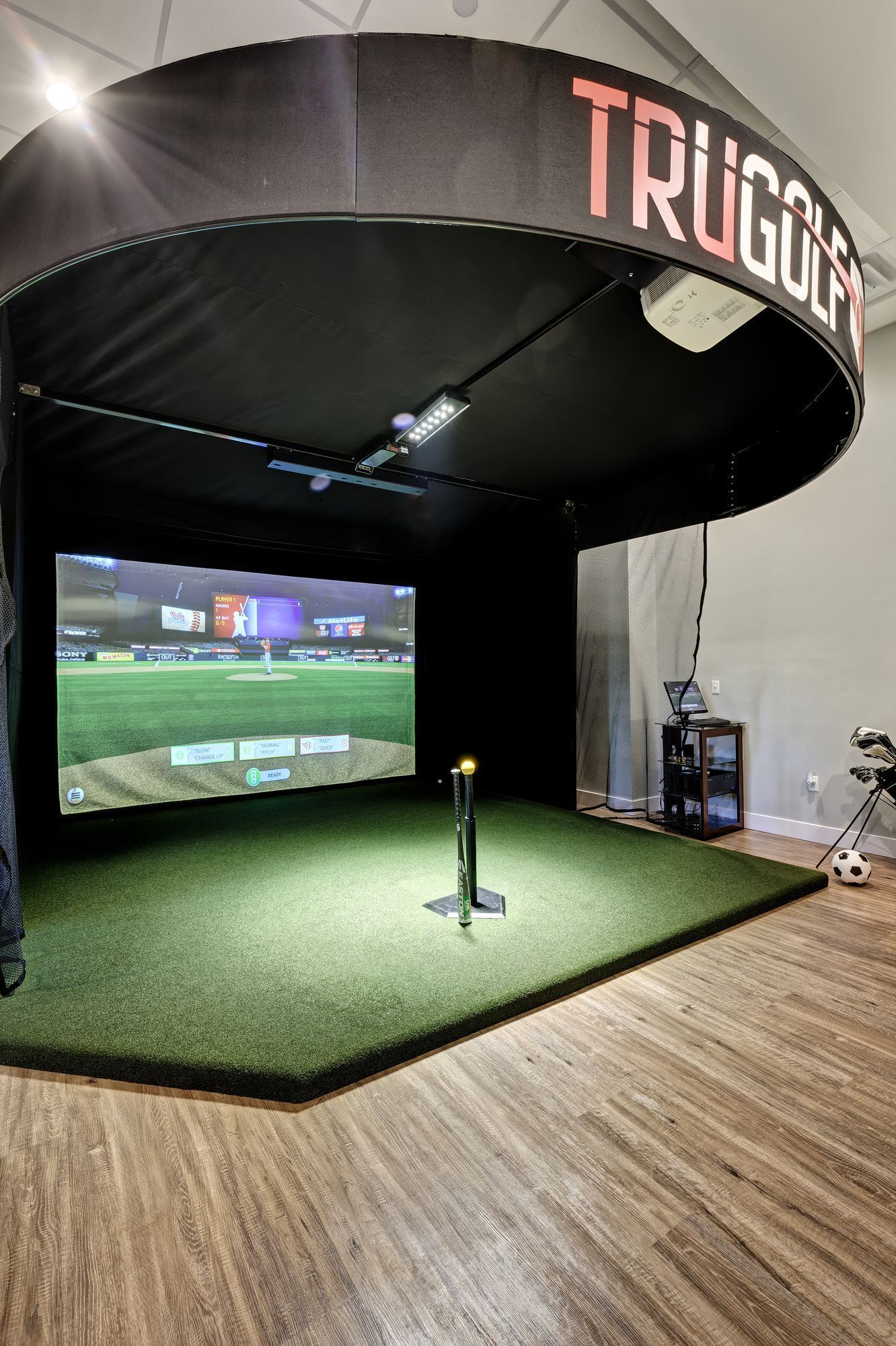 A golf simulator with a large screen displaying a baseball game.