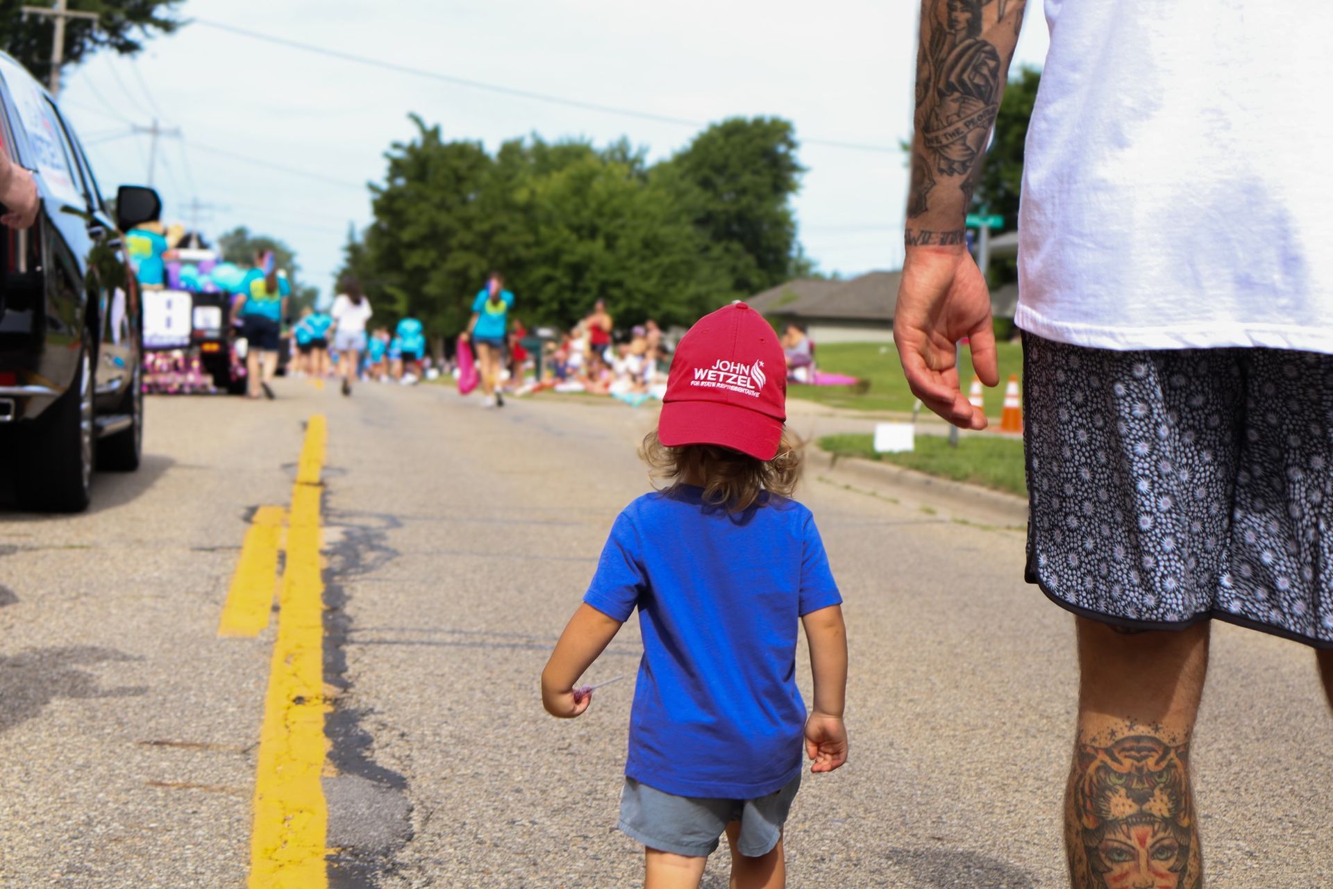 A man and a child are walking down the street holding hands.