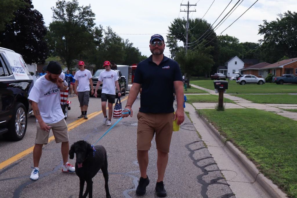 A man is walking a black dog on a leash