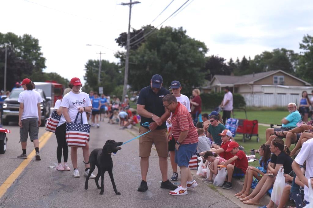 A group of people are standing on the side of the road watching a parade.