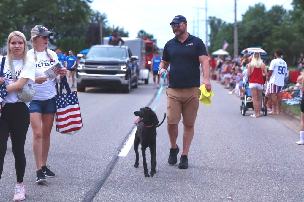 A man is walking a dog on a leash down a street.