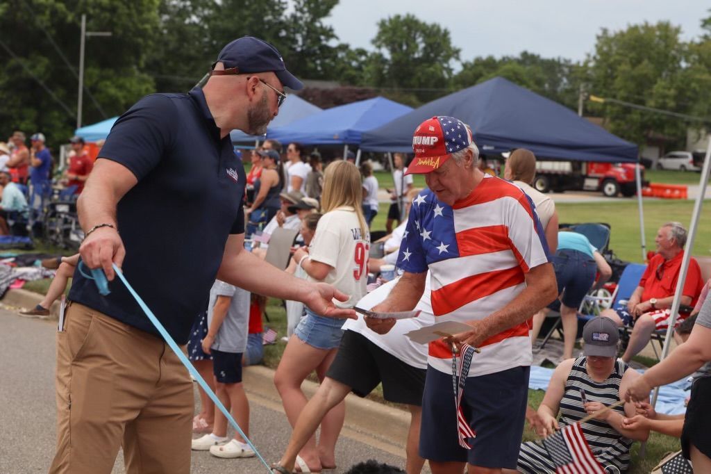 A man is walking a dog on a leash in front of a crowd of people.