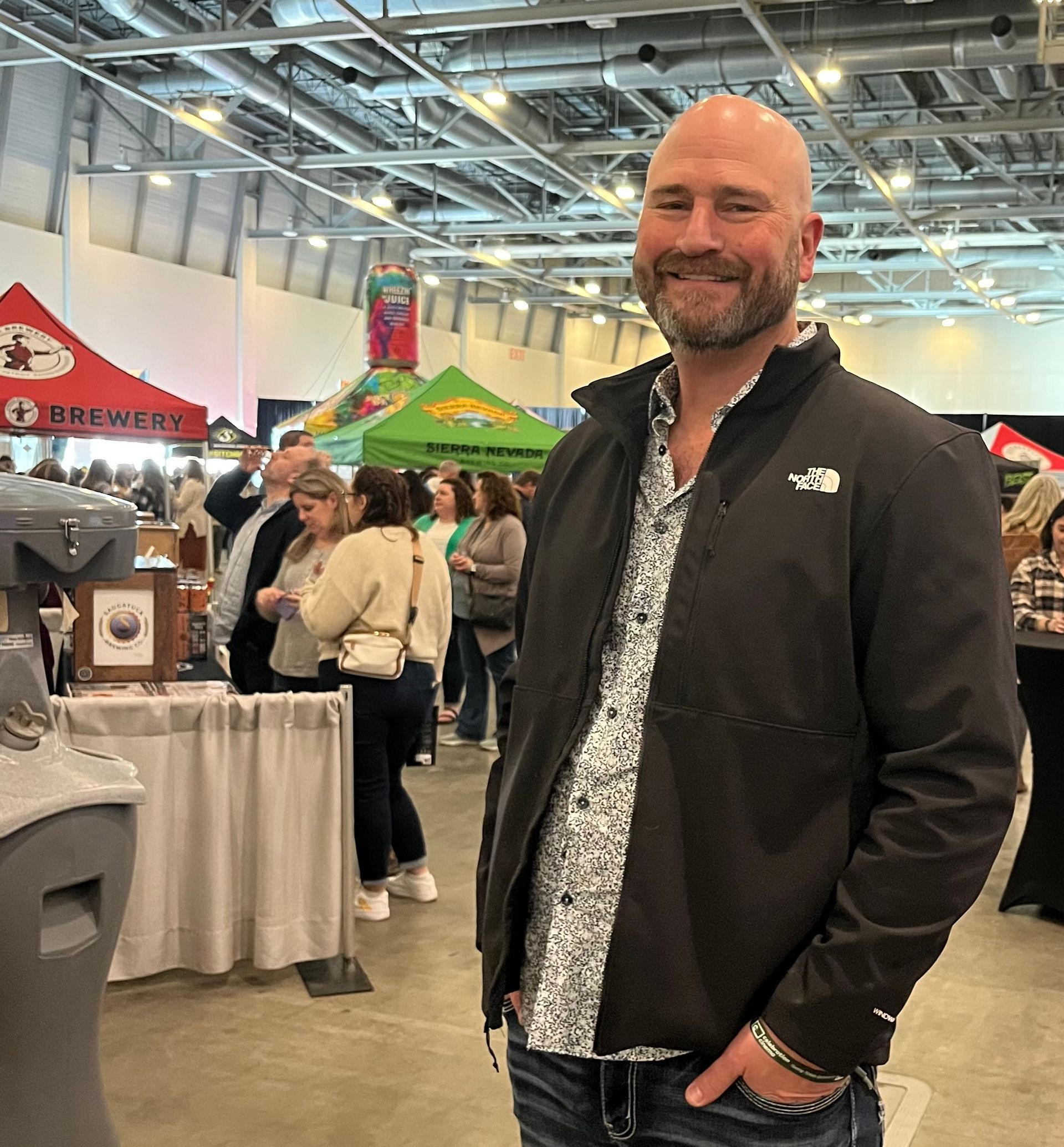 A man in a black jacket is standing in a room with people.