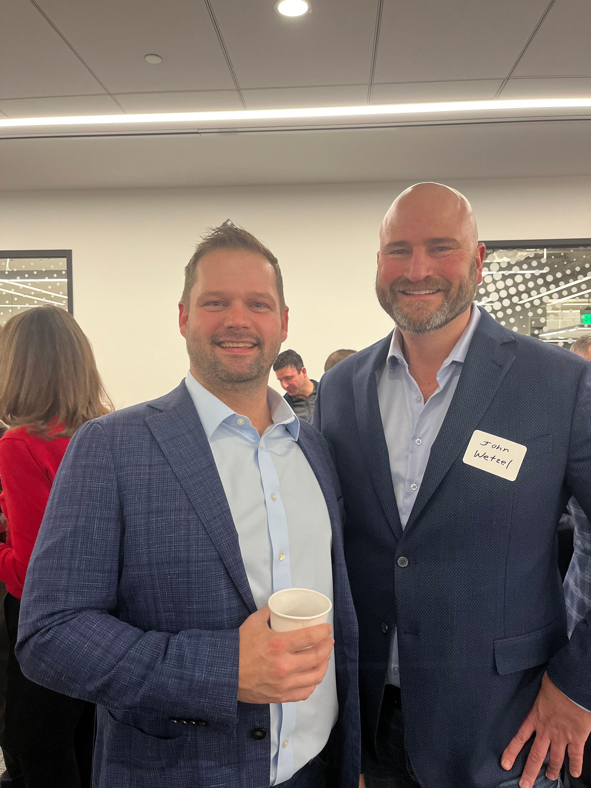 Two men in suits are posing for a picture in a room.