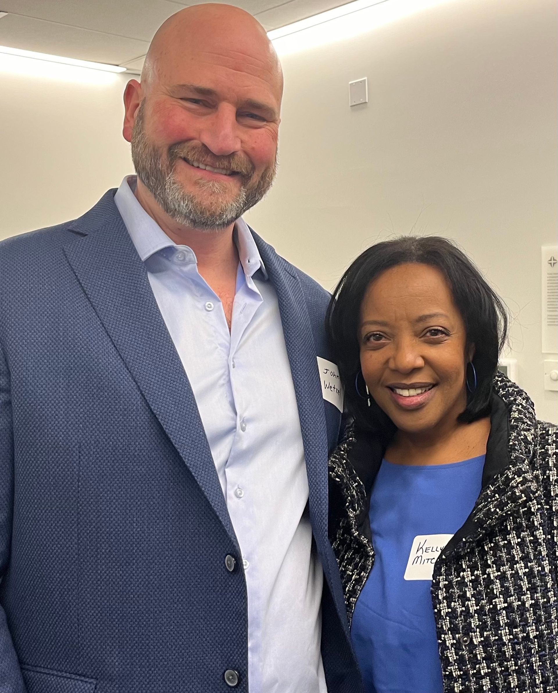 A man in a suit and a woman in a blue shirt are posing for a picture.