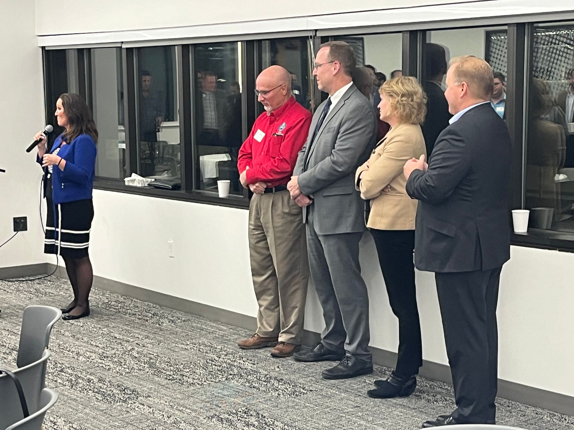 A woman is standing in front of a microphone talking to a group of people.