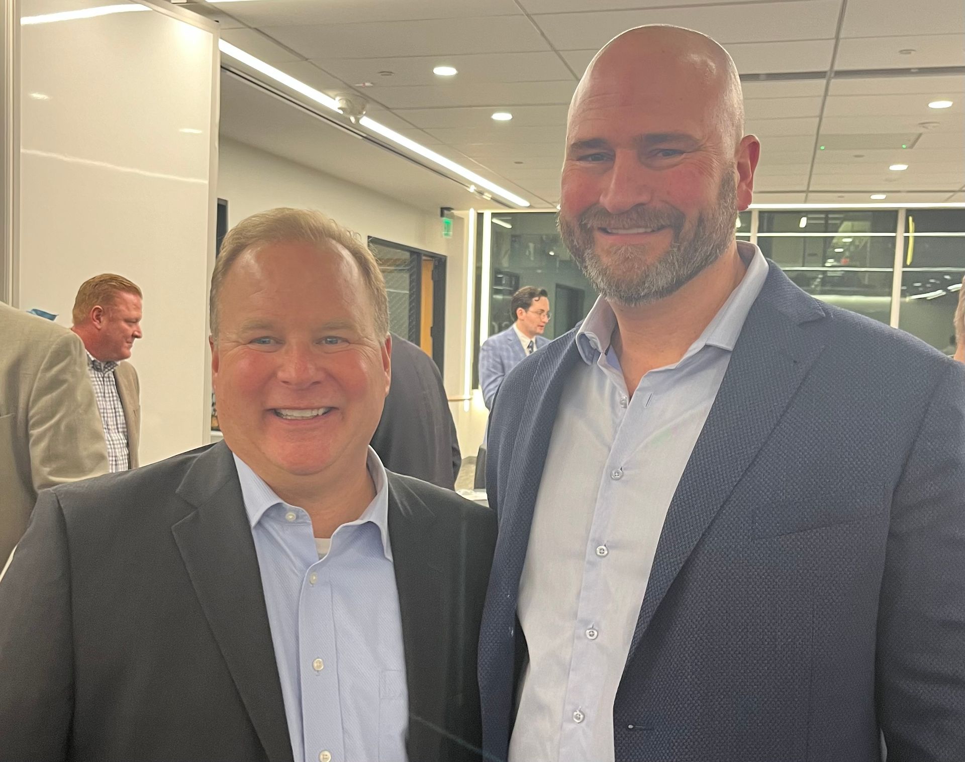 Two men in suits are posing for a picture in a room.