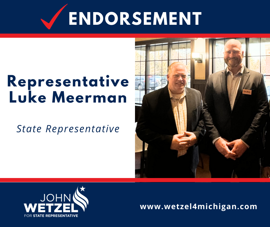 Two men in suits are standing next to each other in front of a window.