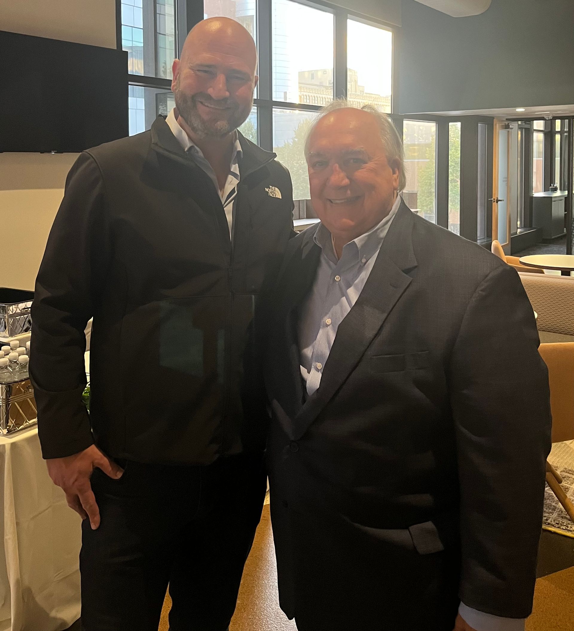 Two men in suits are posing for a picture in a room.