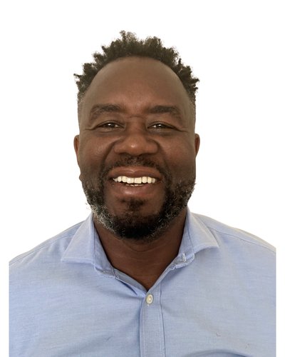 A smiling person wearing a light blue collared shirt, shown from the chest up against a plain white background.