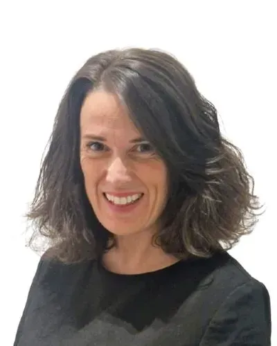 A person with dark, shoulder-length hair smiling warmly against a plain white background.