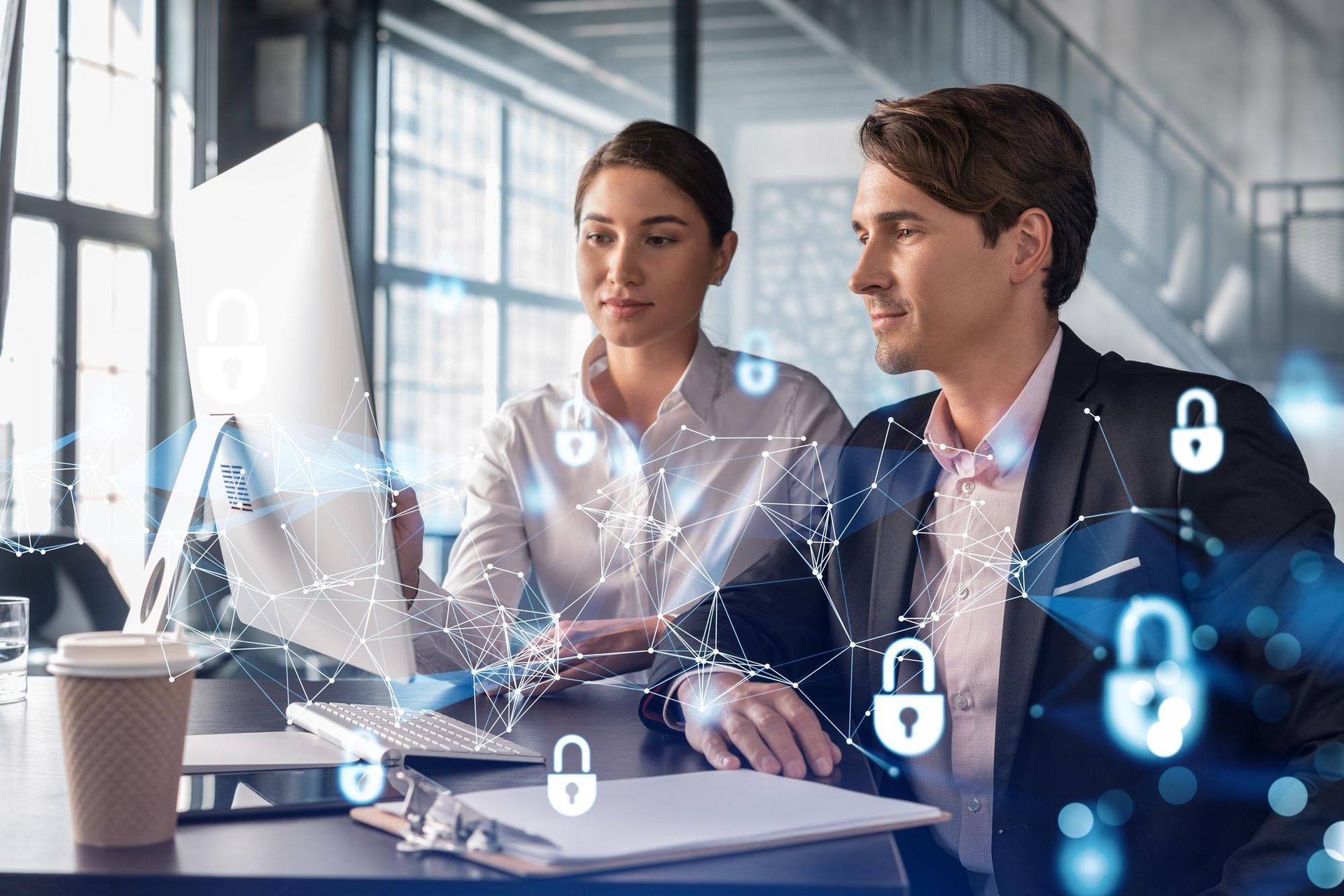 Two professionals work together at a desk, surrounded by glowing, digital lock icons representing cybersecurity.