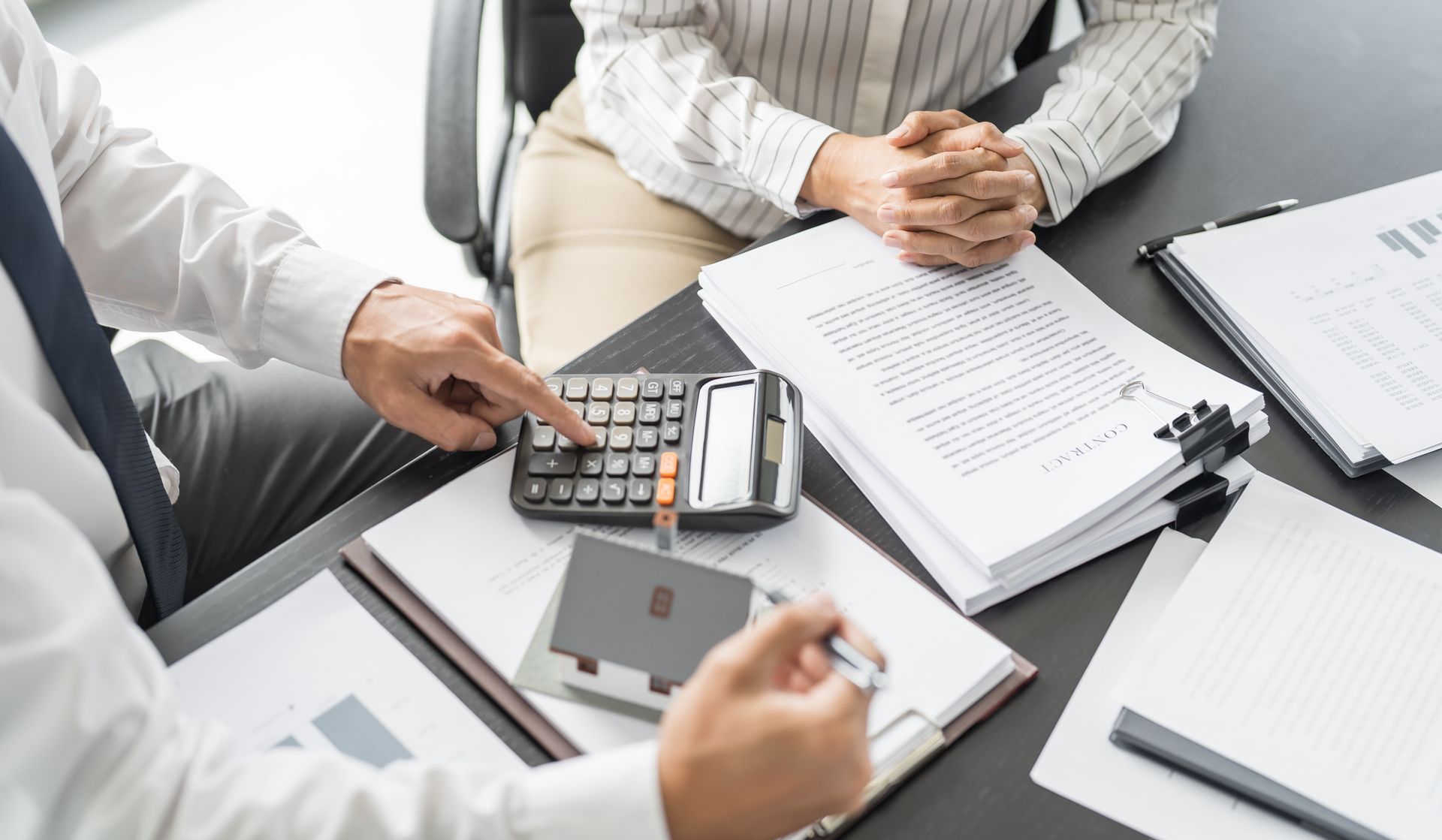 Two people at a desk review documents and use a calculator