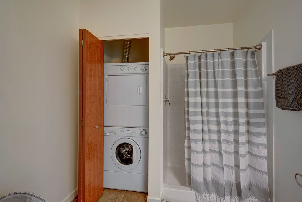 A bathroom with a washer and dryer stacked on top of each other.