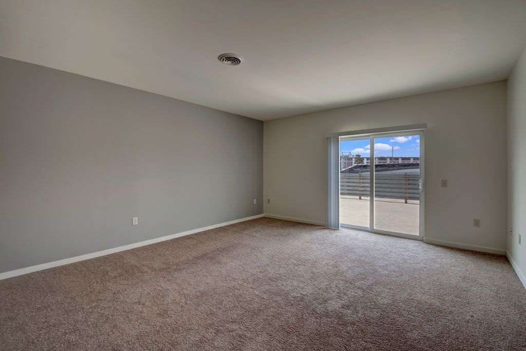 An empty living room with a sliding glass door and a balcony.