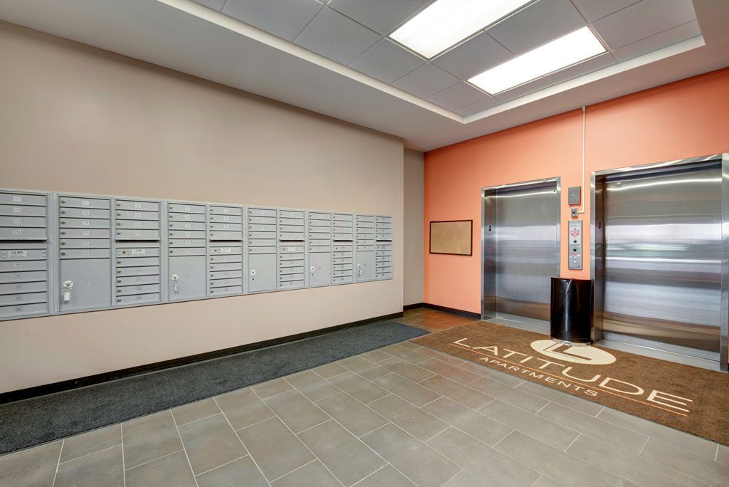 A lobby with two elevators and a wall of mailboxes