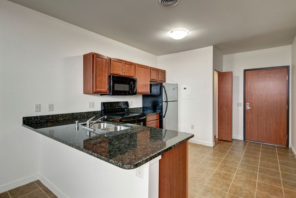 A kitchen with granite counter tops , stainless steel appliances , and wooden cabinets.