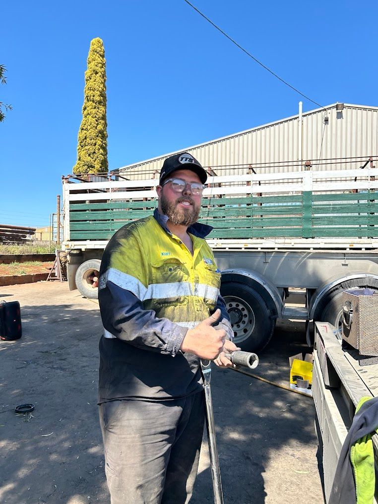 A Man is Standing in Front of a Truck Holding a Pipe — Trucks On The Run Pty Ltd in Warwick, QLD