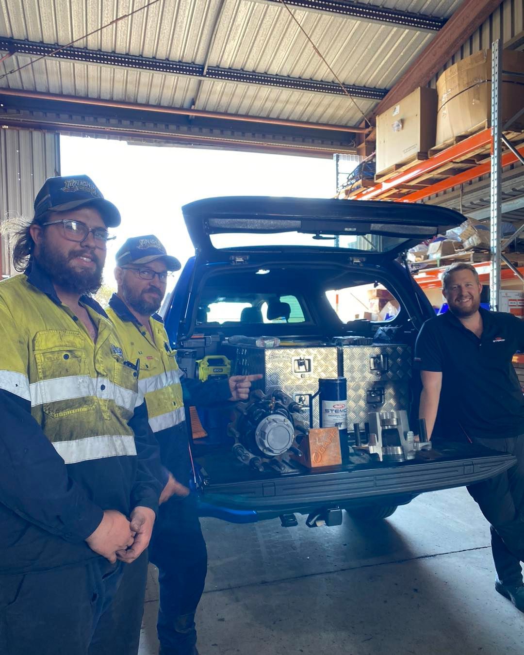 A Group of Men Are Standing Next to a Truck in a Garage — Trucks On The Run Pty Ltd in Oakey, QLD