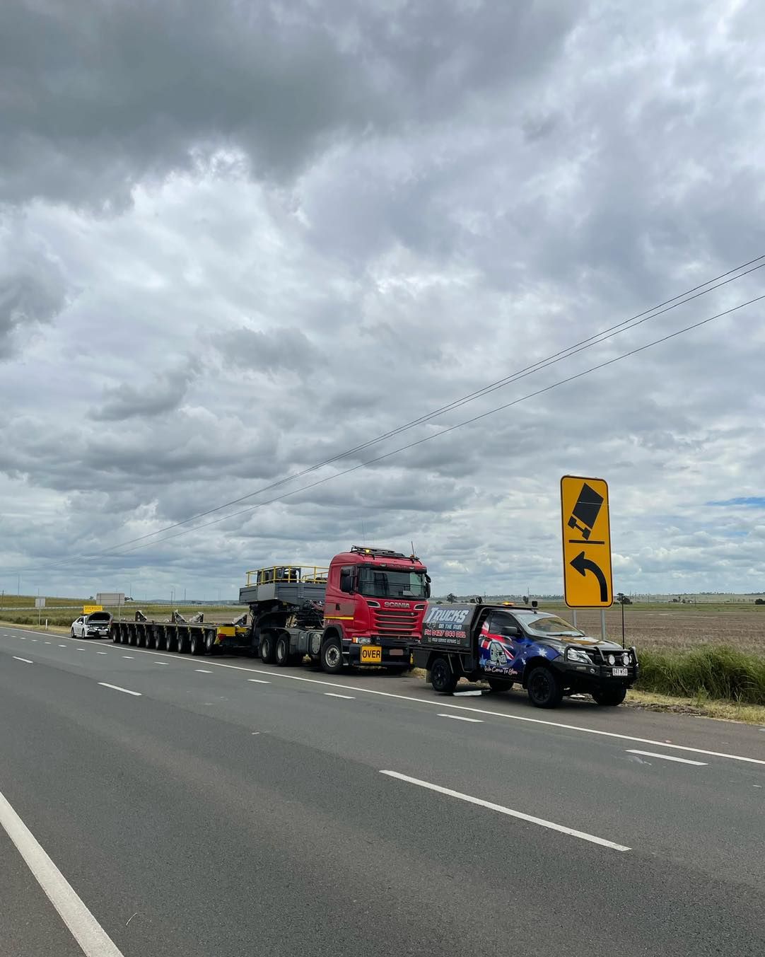 A Red Truck is Driving Down a Highway Next to a Yellow Sign — Trucks On The Run Pty Ltd in Pittsworth, QLD