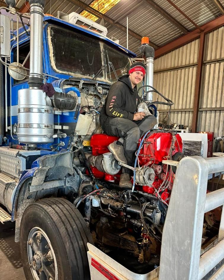 A Man is Sitting on the Engine of a Semi Truck — Trucks On The Run Pty Ltd in Kingsthorpe, QLD