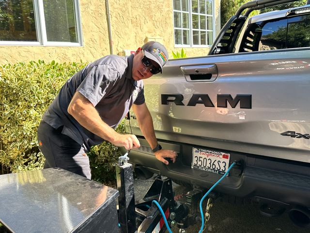 A man is working on the back of a ram truck.