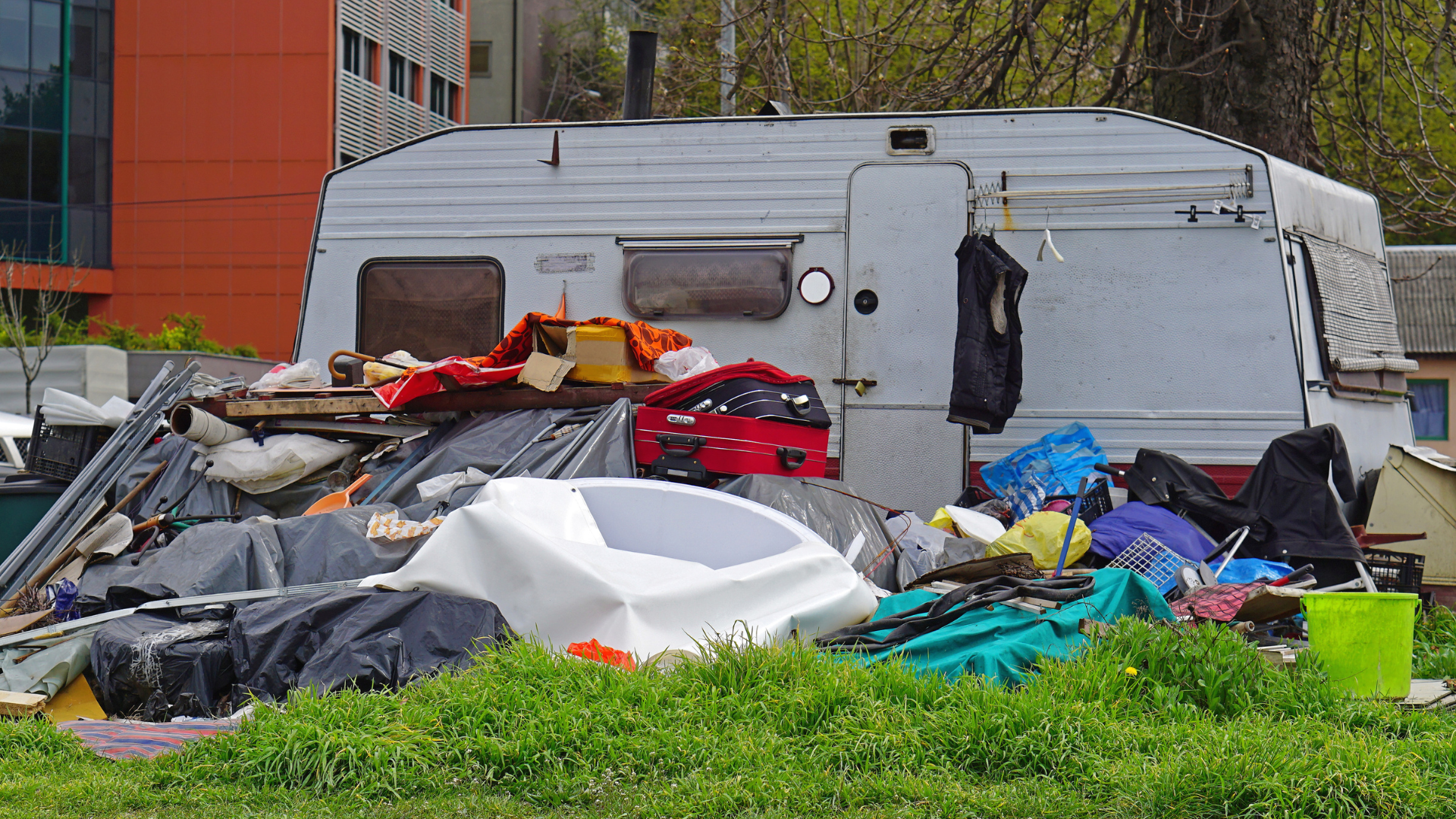 A pile of trash is sitting in the grass in front of a trailer.