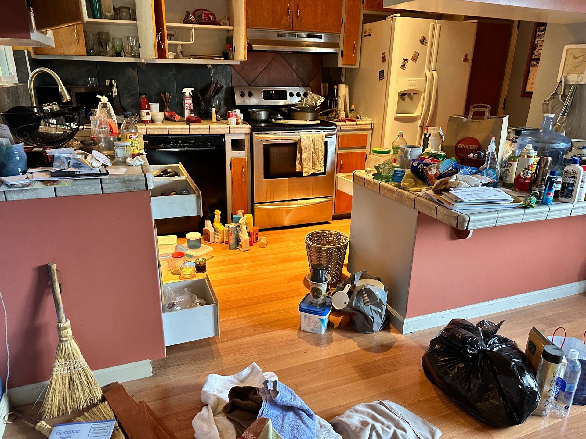 A very messy kitchen with a stove and refrigerator