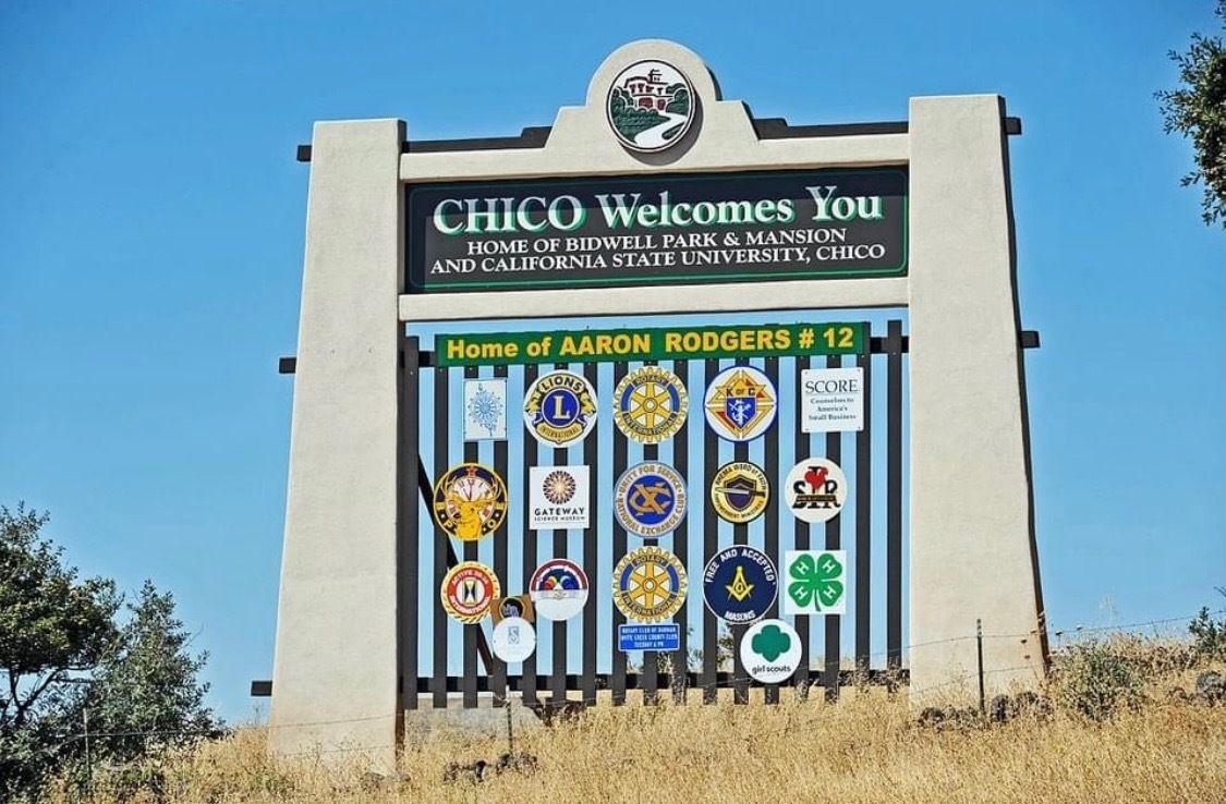 A yellow and black excavator is demolishing a building.