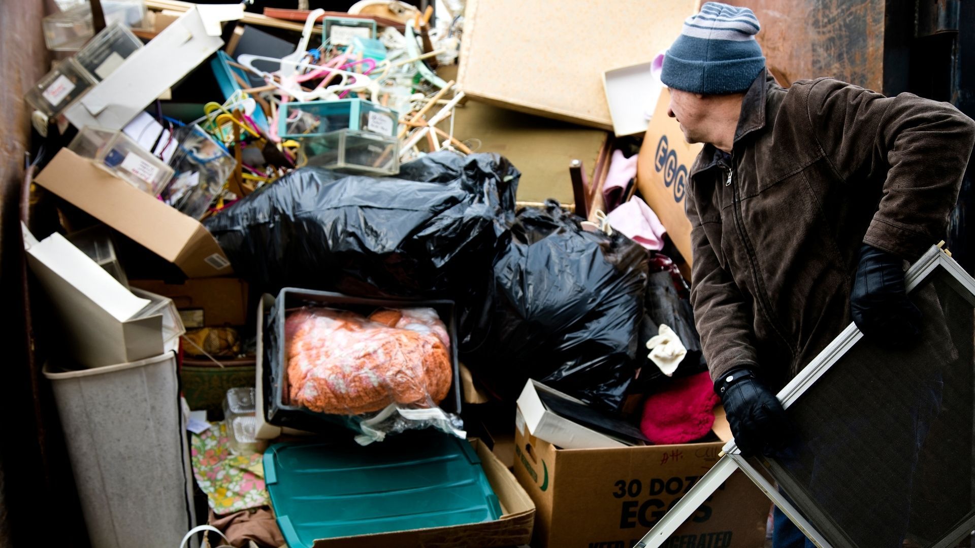 A man is standing in front of a pile of trash.