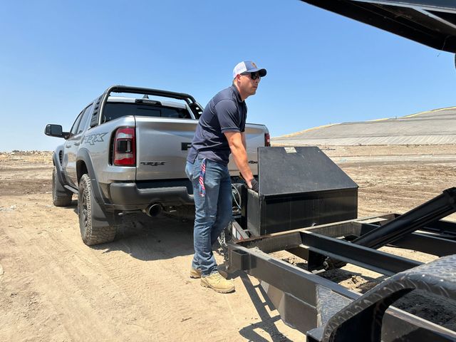 A man is loading a trailer into a truck.