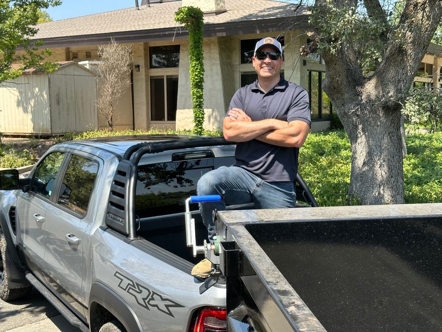 A man is standing in front of a truck with his arms crossed.