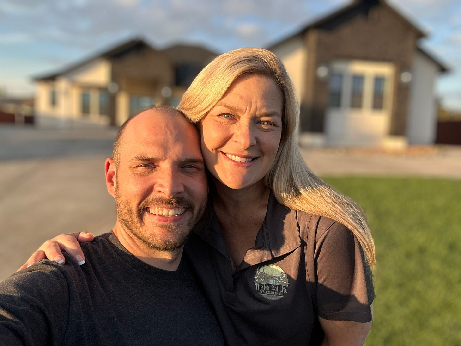 A man and a woman are posing for a picture in front of a house.