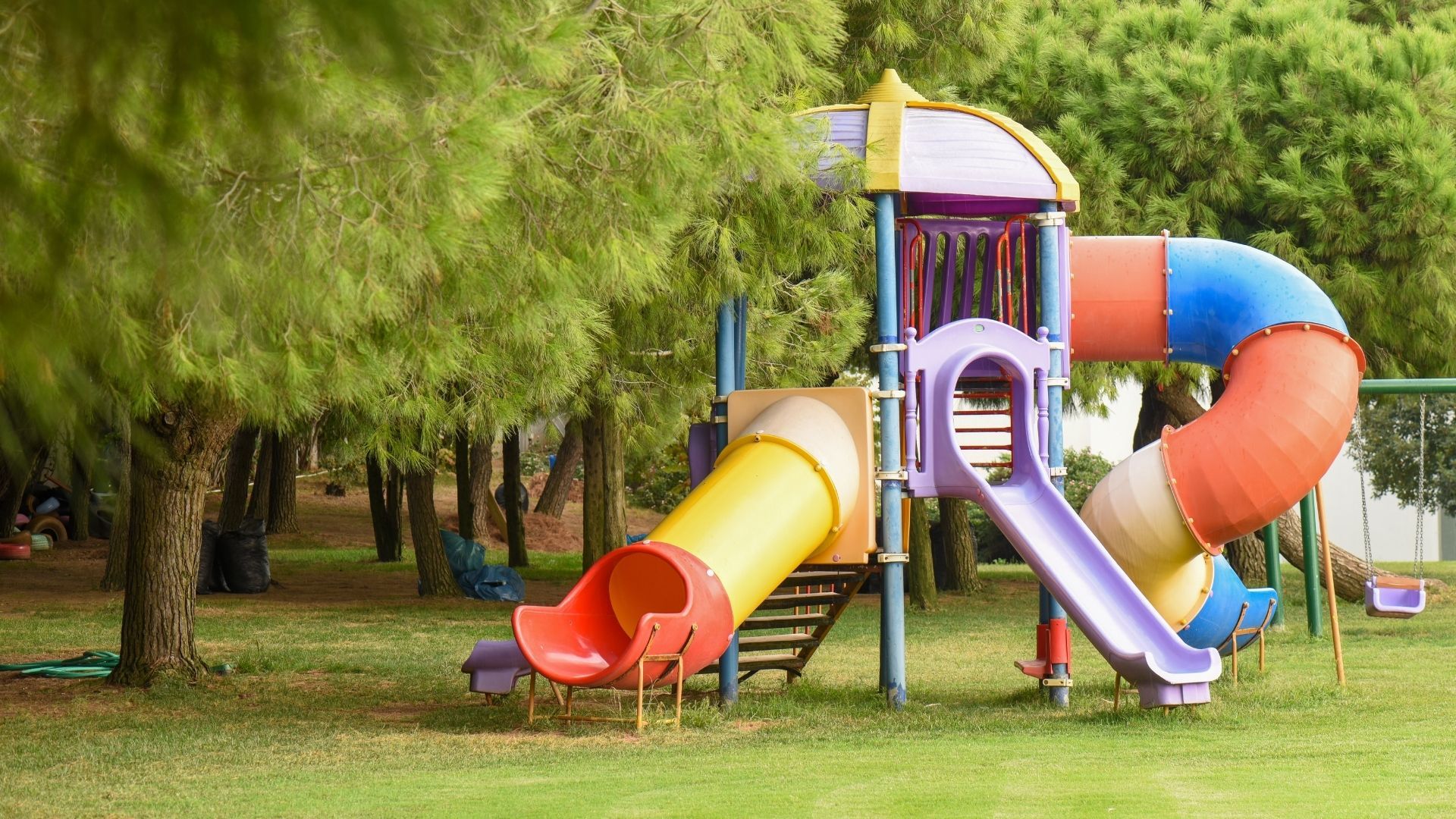 A colorful playground set in a park with trees in the background.