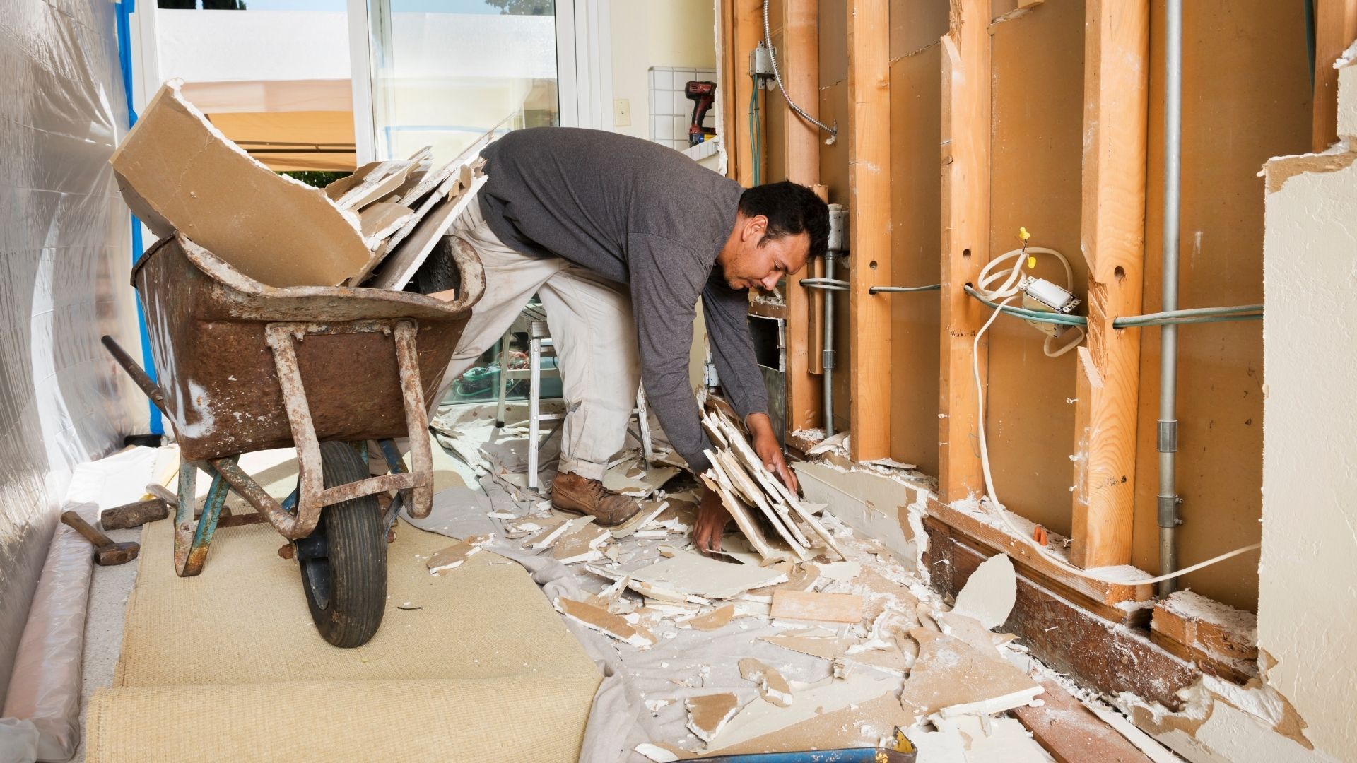 A man is working in a room with a wheelbarrow.